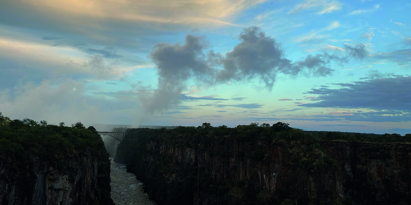 Victoria Falls, between Zambia and Zimbabwe, is a stunning sight at dawn. The rising sun bathes the rocky edge in golden light as the Zambezi River flows gracefully over, creating rainbows in the mist. It's a powerful and beautiful testament to nature's majesty.