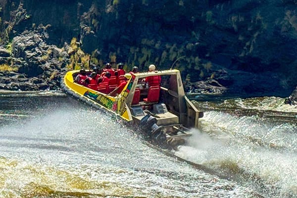 jet-boat-zambezi-river-victoria-falls-zimbabwe-adventure High-speed jet boat adventure on Zambezi River near Victoria Falls Zimbabwe showcasing adrenaline water sports and adventure activities in dramatic gorge