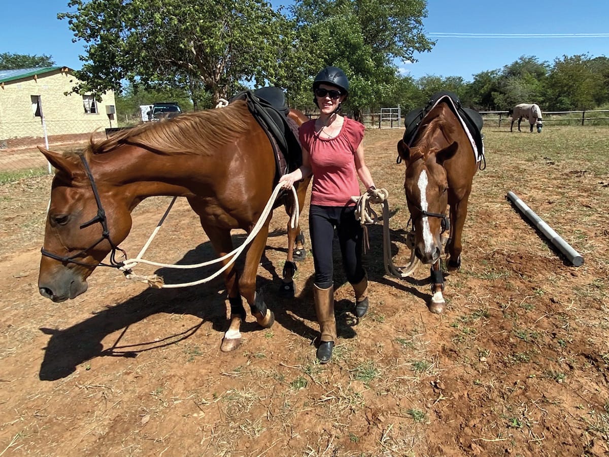 Confident rider leading calm brown and white horses at Wild Bhiza stables Zimbabwe
