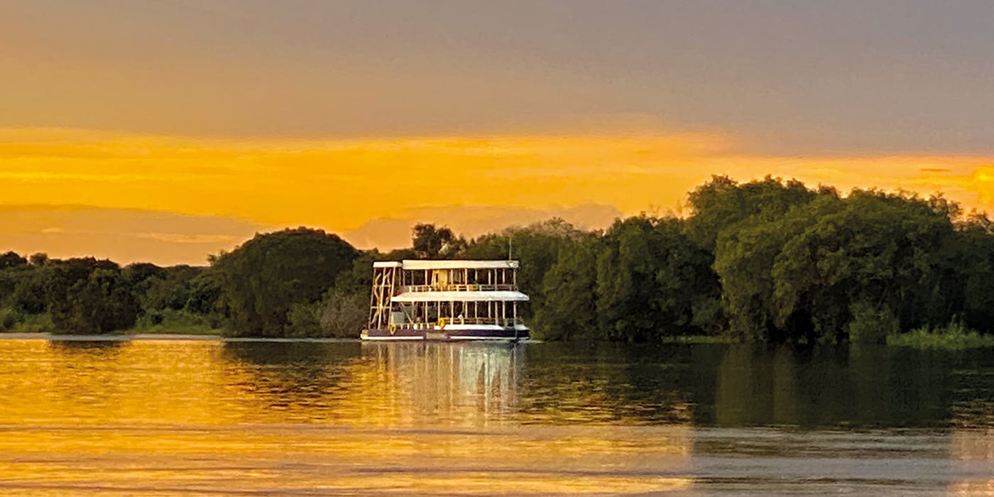 Double-decker sunset cruise boat on Zambezi River at golden hour near Victoria Falls Zimbabwe